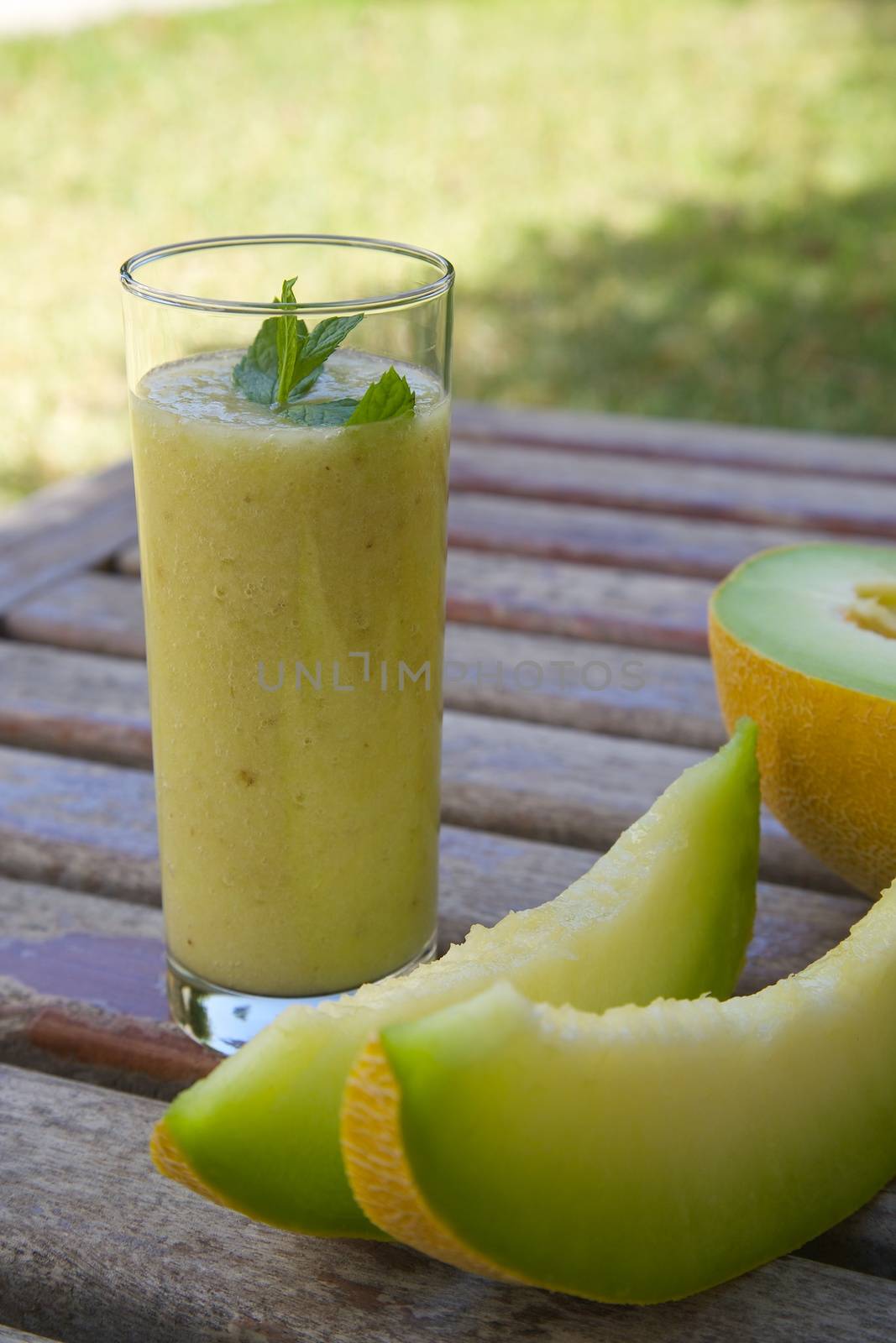A glass of melon smoothie on an old wooden surface