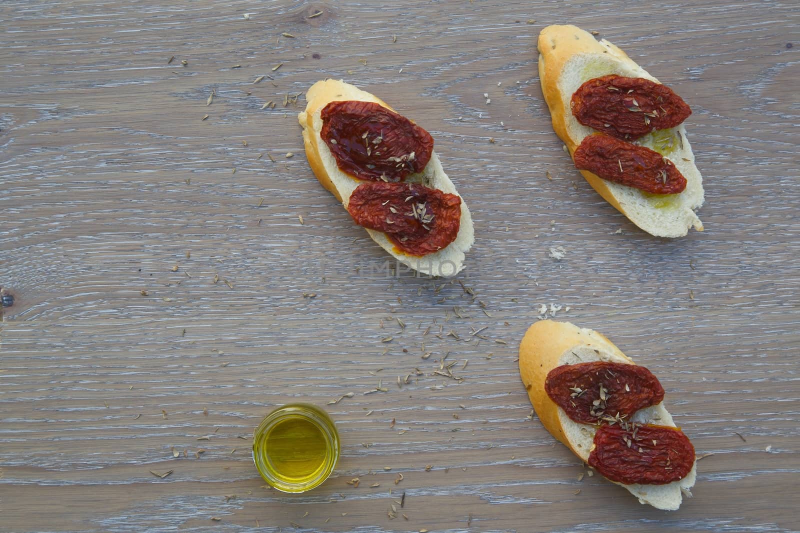 Flavorful starter - sun-dried red tomatoes on the pieces of French baguette by tolikoff_photography