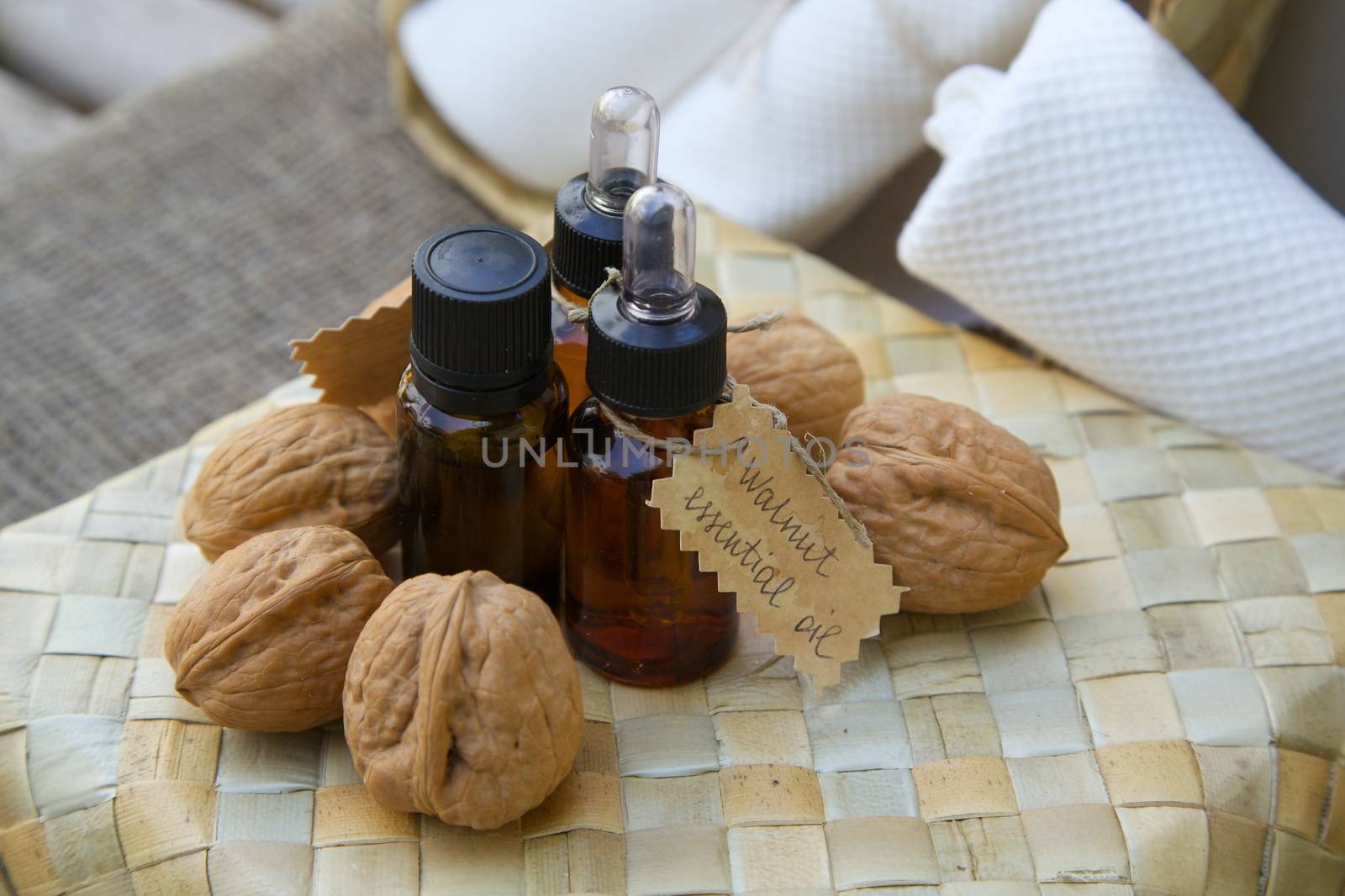 Bottle of walnut essential oil on the woven surface. Walnuts in the background