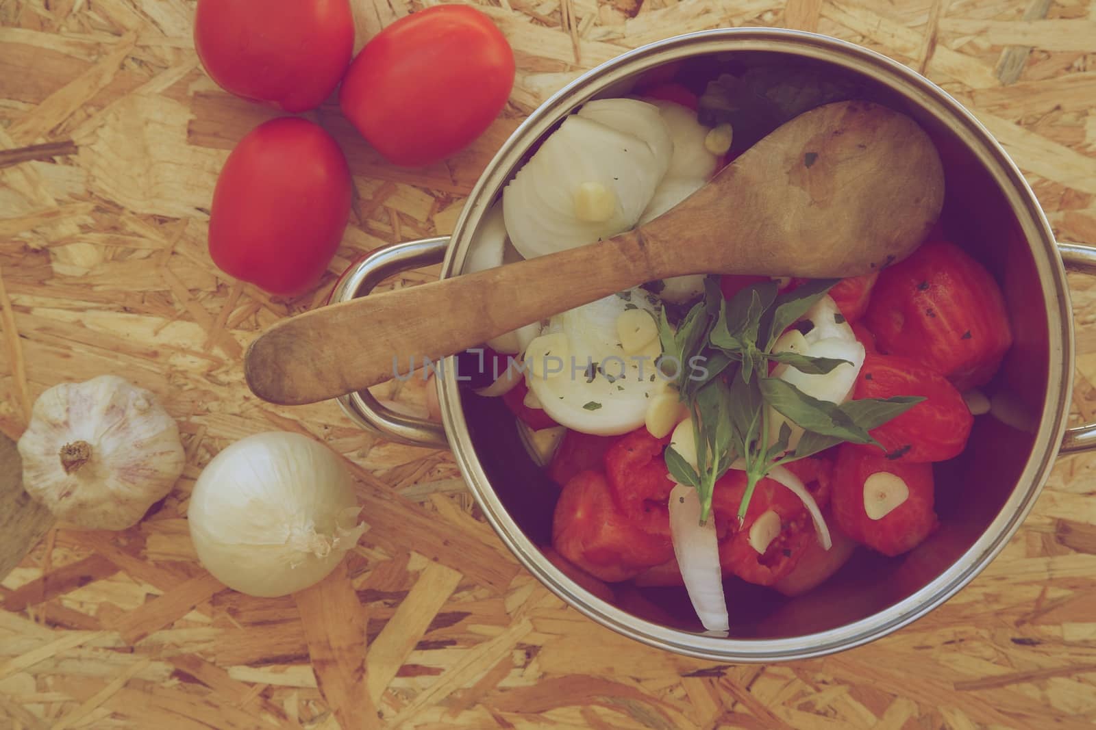 Prepared food ingredients for cooking Italian tomato sauce - salsa. Ingredients are placed in the pot which is on the wooden surface. Vintage photo