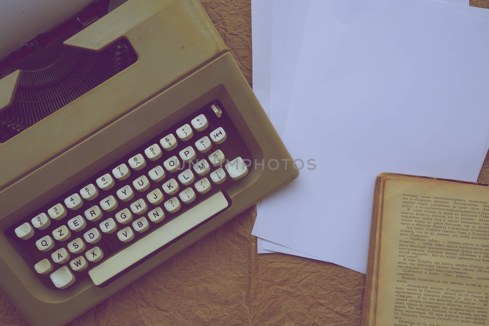 Typing machine, white sheets of paper,old book on an old paper surface. Vintage