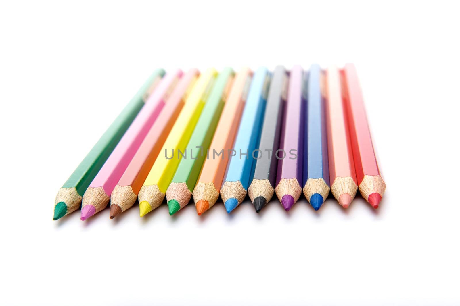 Isolated horizontal arrangement of twelve vividly coloured pencils on the white background