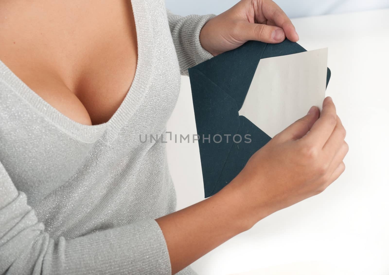 Horizontal close-up of a seductive young woman putting a note into the envelope