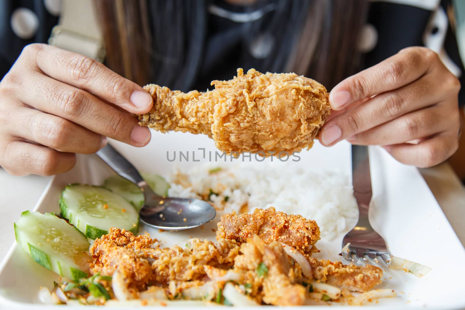 Hand holding Fried chicken and eating in the restaurant