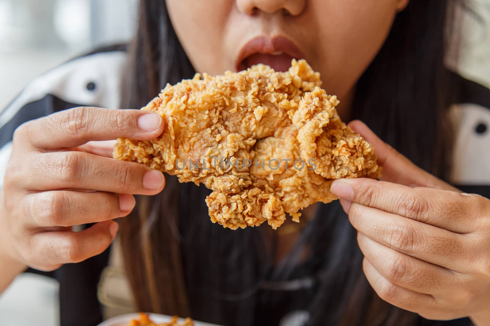 Hand holding Fried chicken and eating in the restaurant