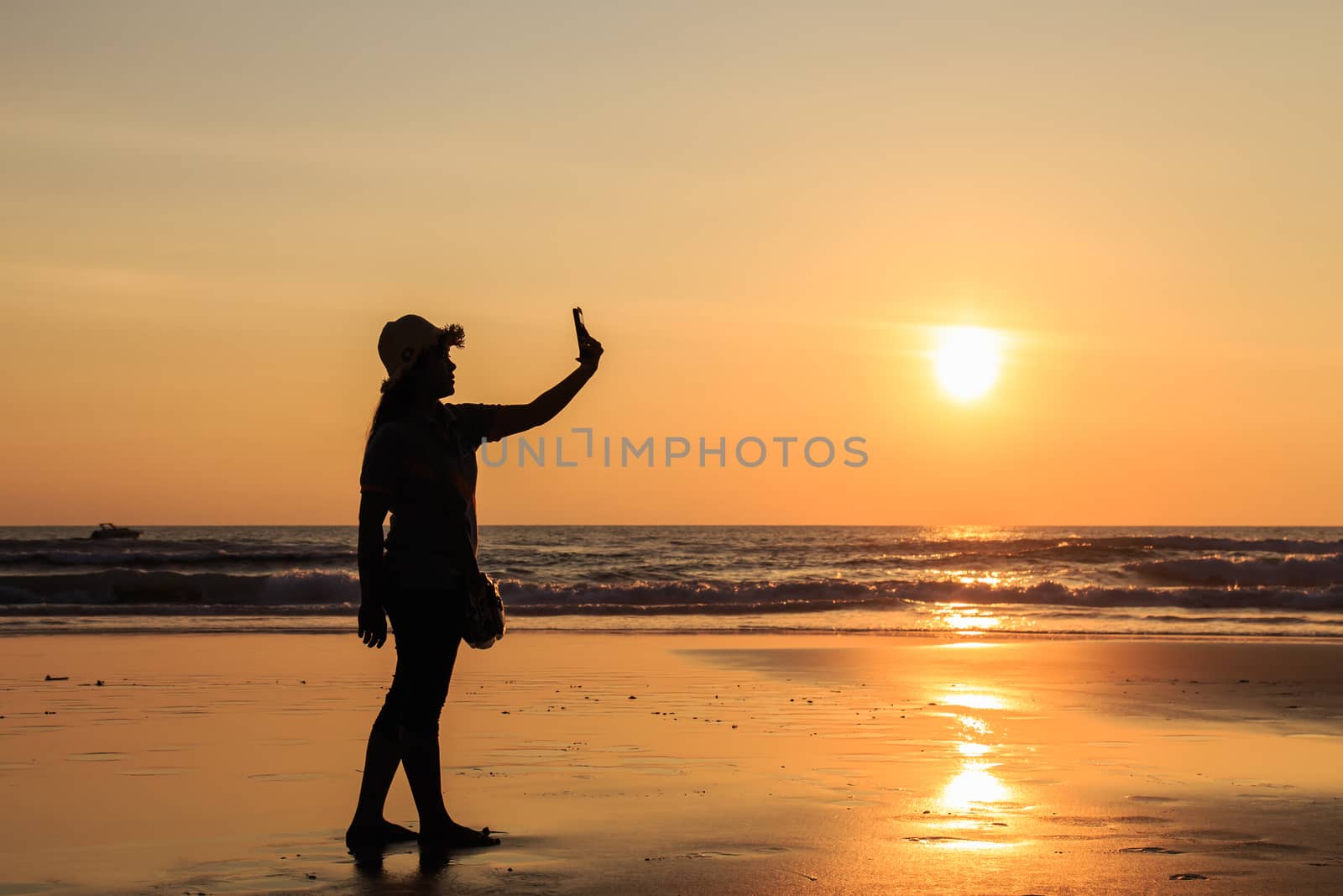 Silhouette of Thai Woman using smartphone at the beach in sunset time