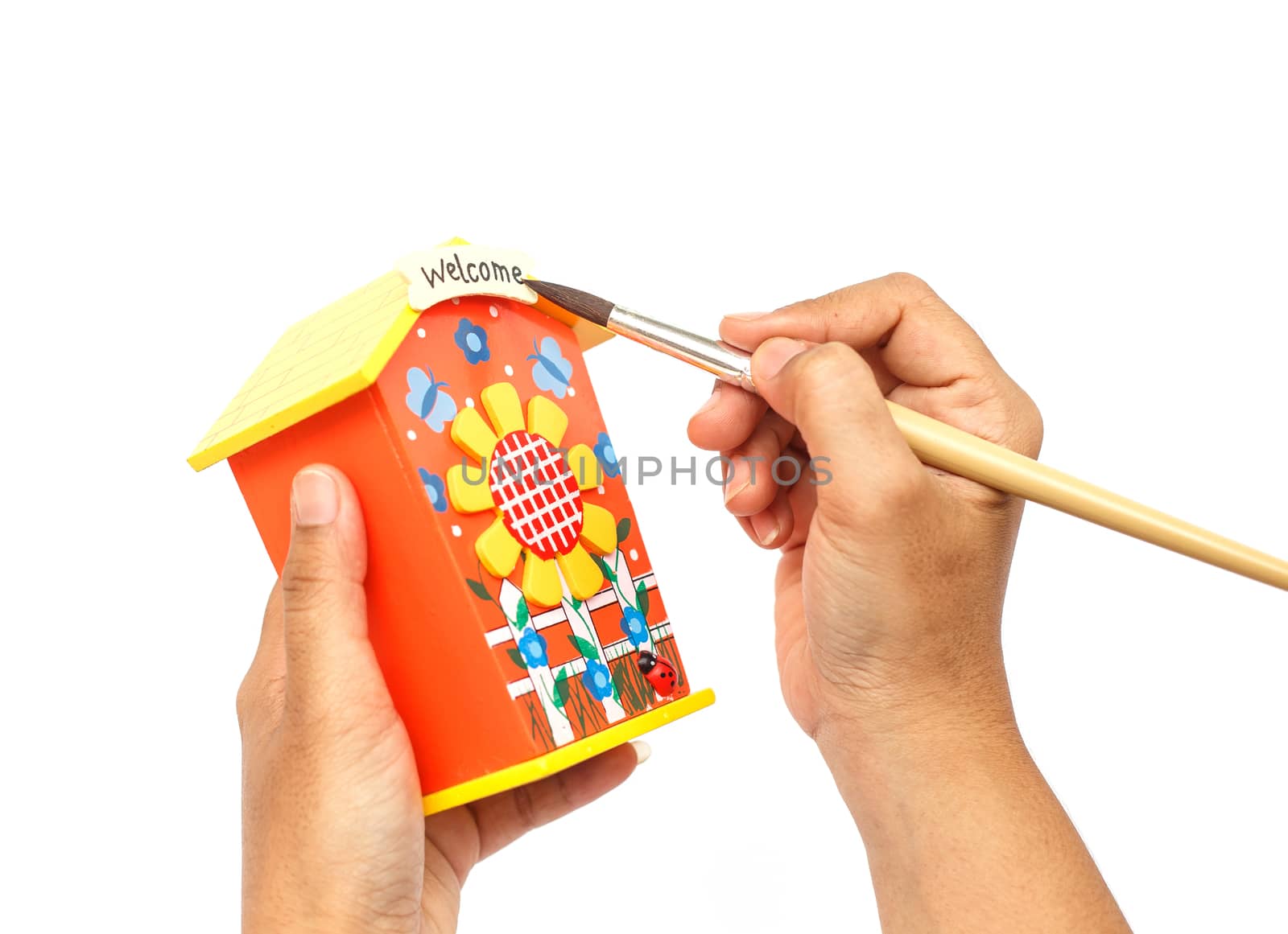 Hand holding paintbrush and painting isolated on white background