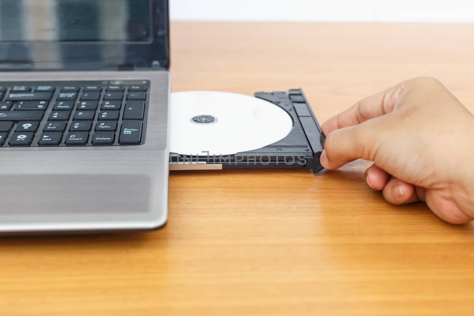 Hand inserting a cd on laptop on table