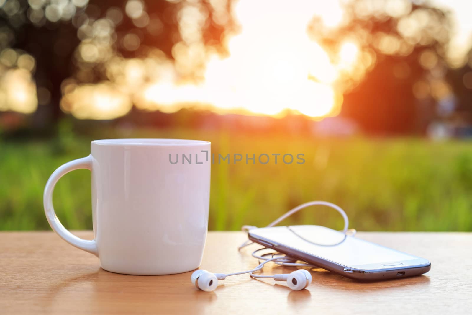 Coffee cup and smartphone on the table in sunset time