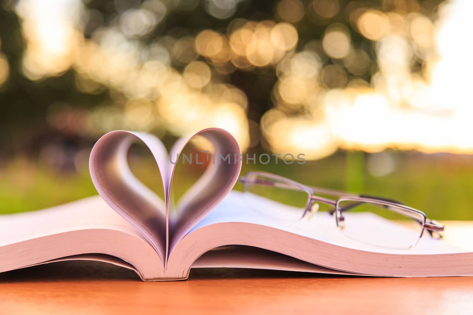 Close up book and glasses on table in sunset time