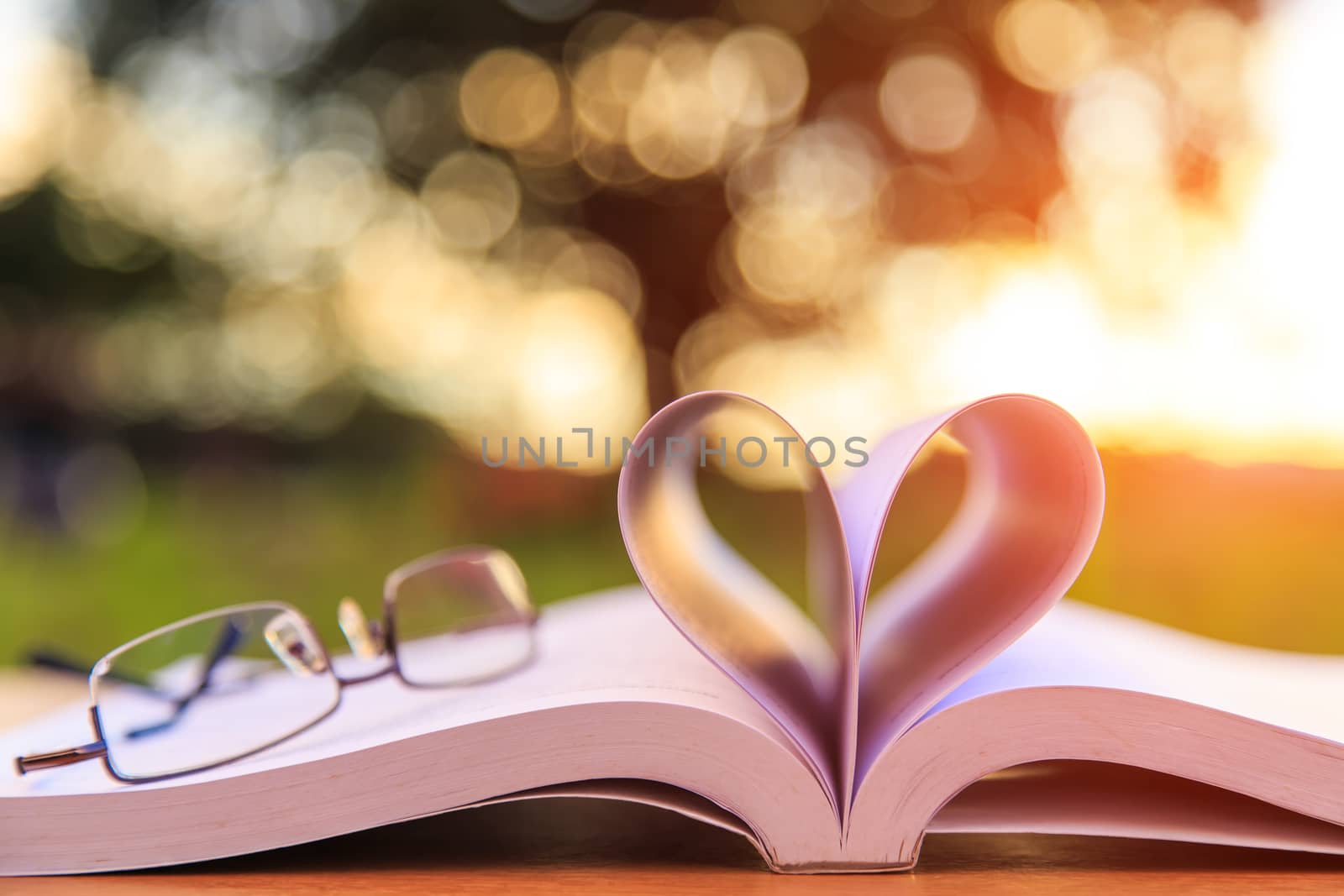 Close up book and glasses on table in sunset time