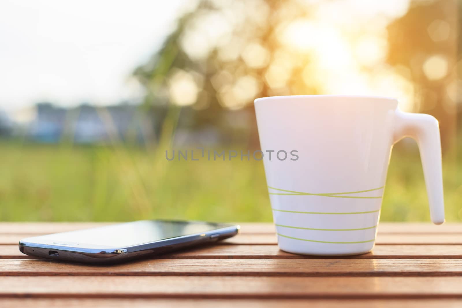 Coffee cup and smartphone on the table in sunset time