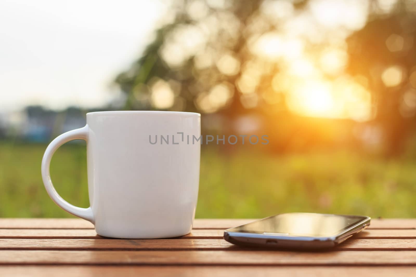 Coffee cup and smartphone on the table in sunset time