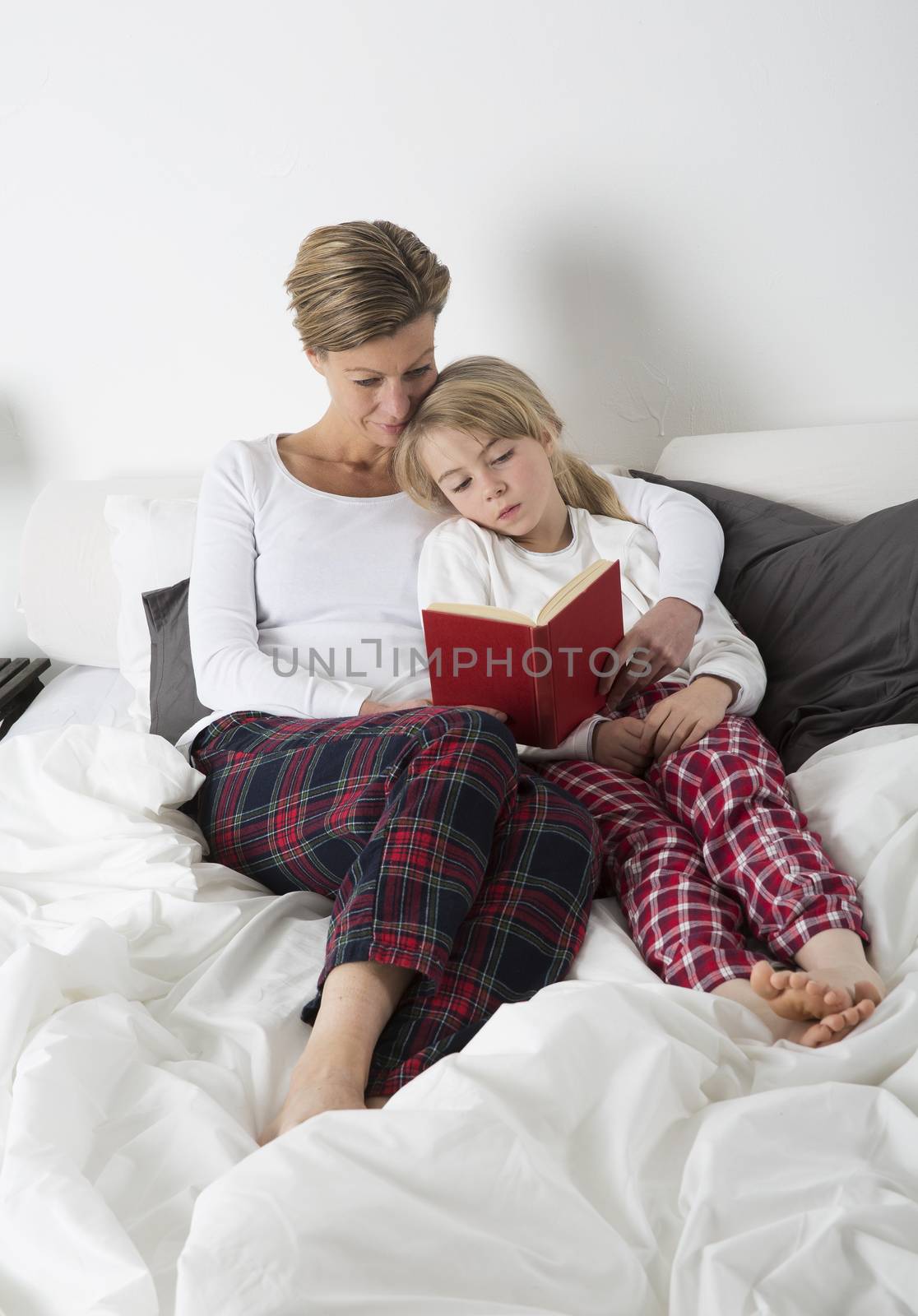 Mother and Daughter reading a book in bed