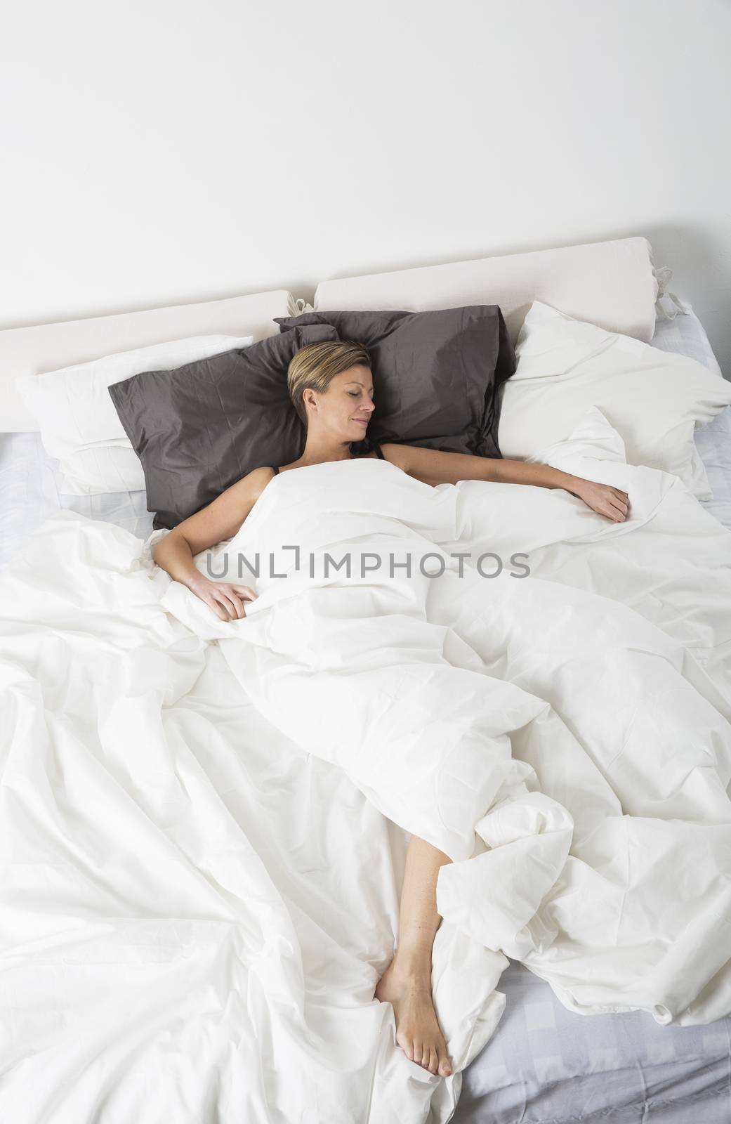 Woman sleeping in a white bedroom environment from high angle view