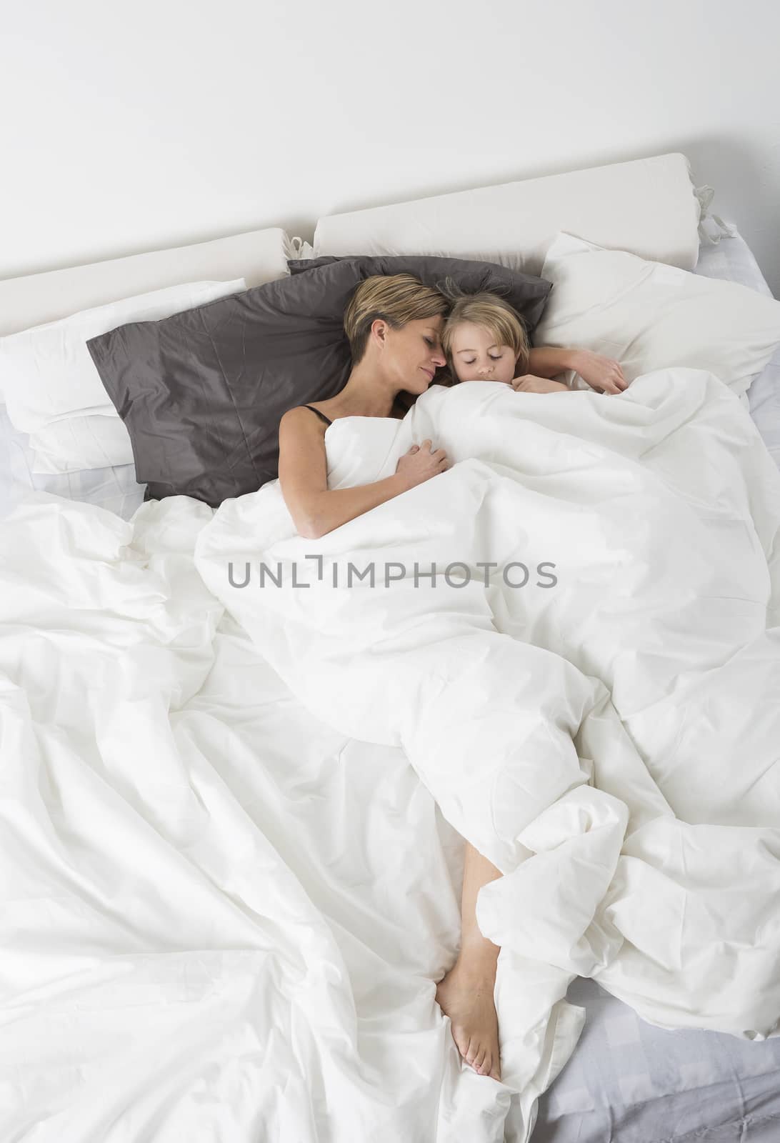 Mother and Daughter sleeping in a white bedroom from high angle view