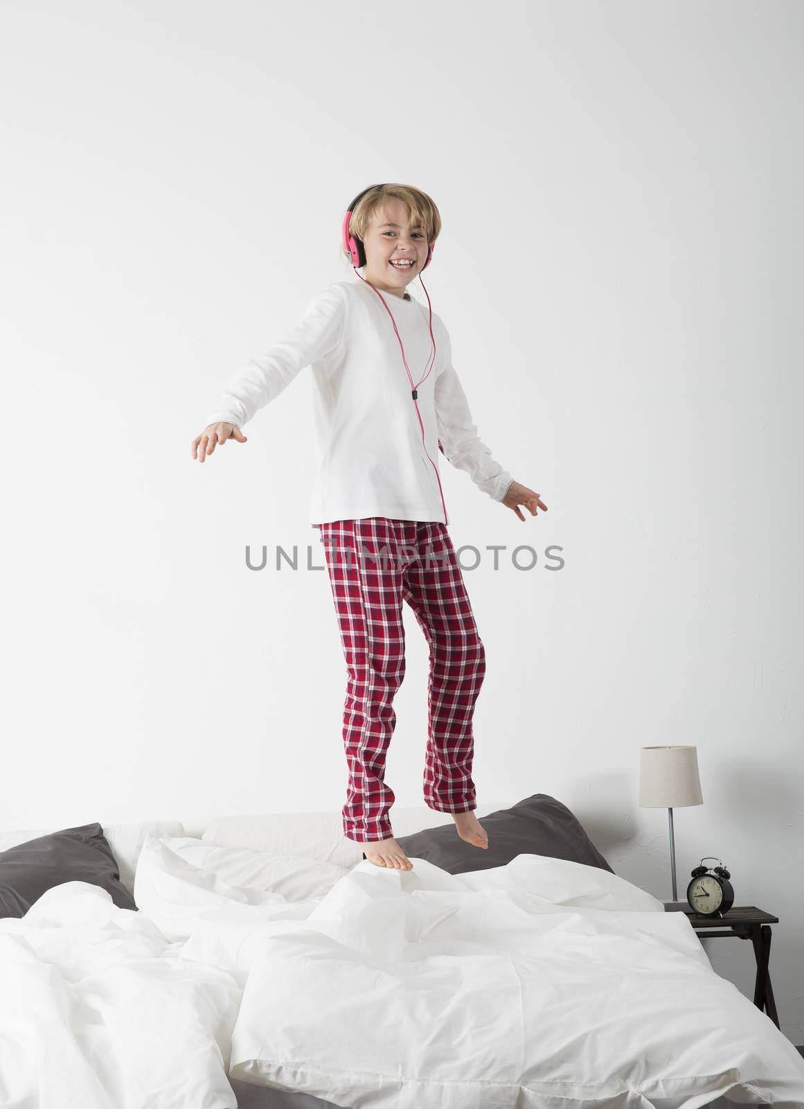 Little girl with Headphones jumping in bed by gemenacom