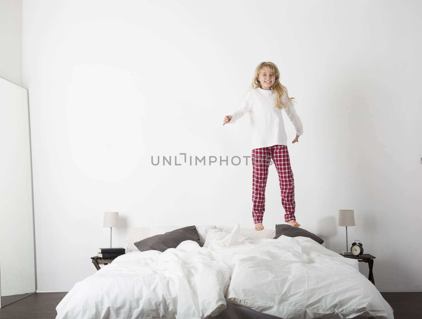Happy little Girl jumping in bed by gemenacom