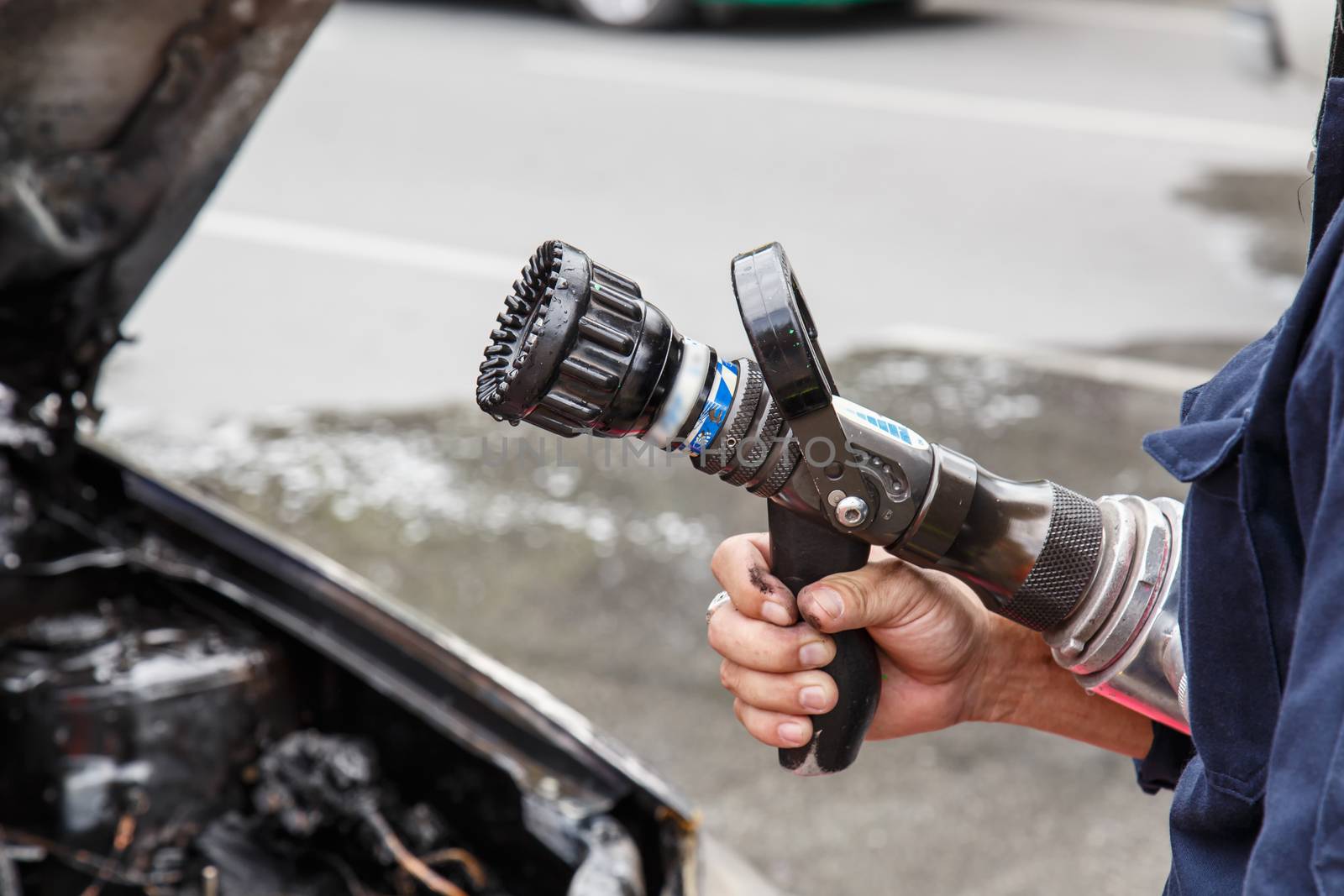 Hand holding water hose to prevent fire on car