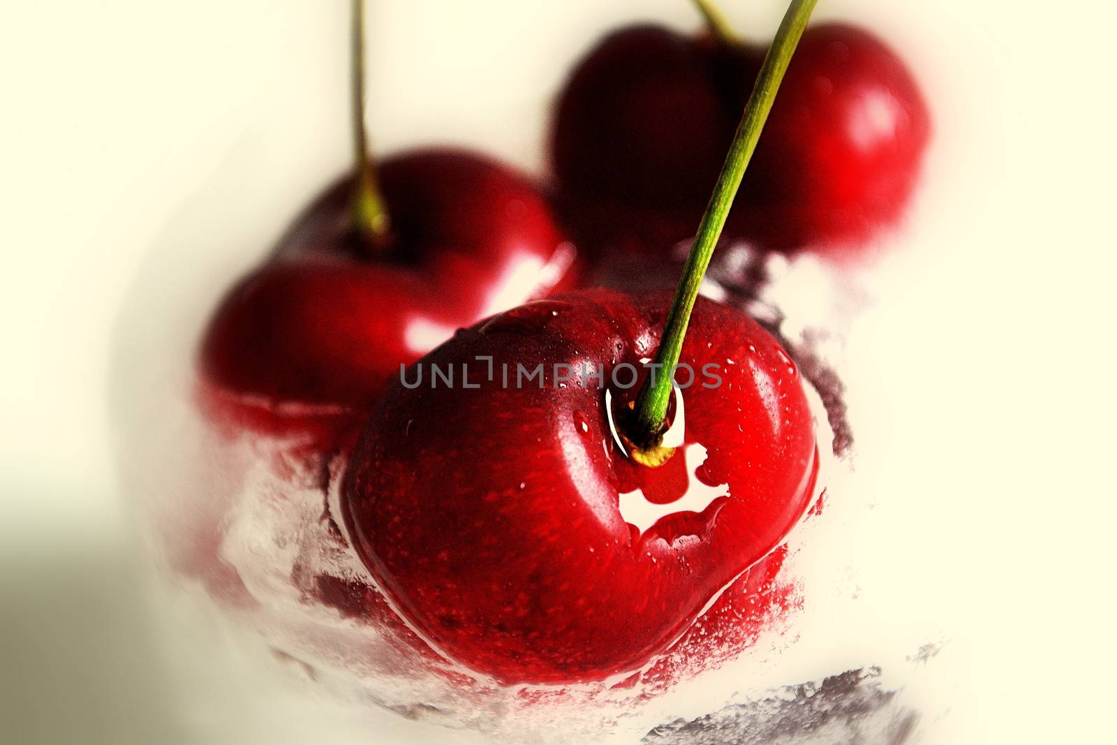 Close up of three red inviting cherries plunging into liquid