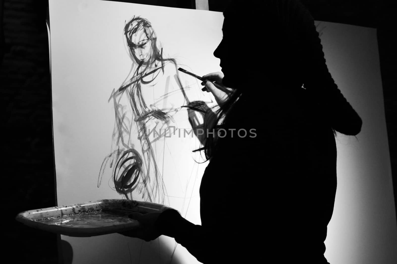 Silhouetted woman painting over canvas