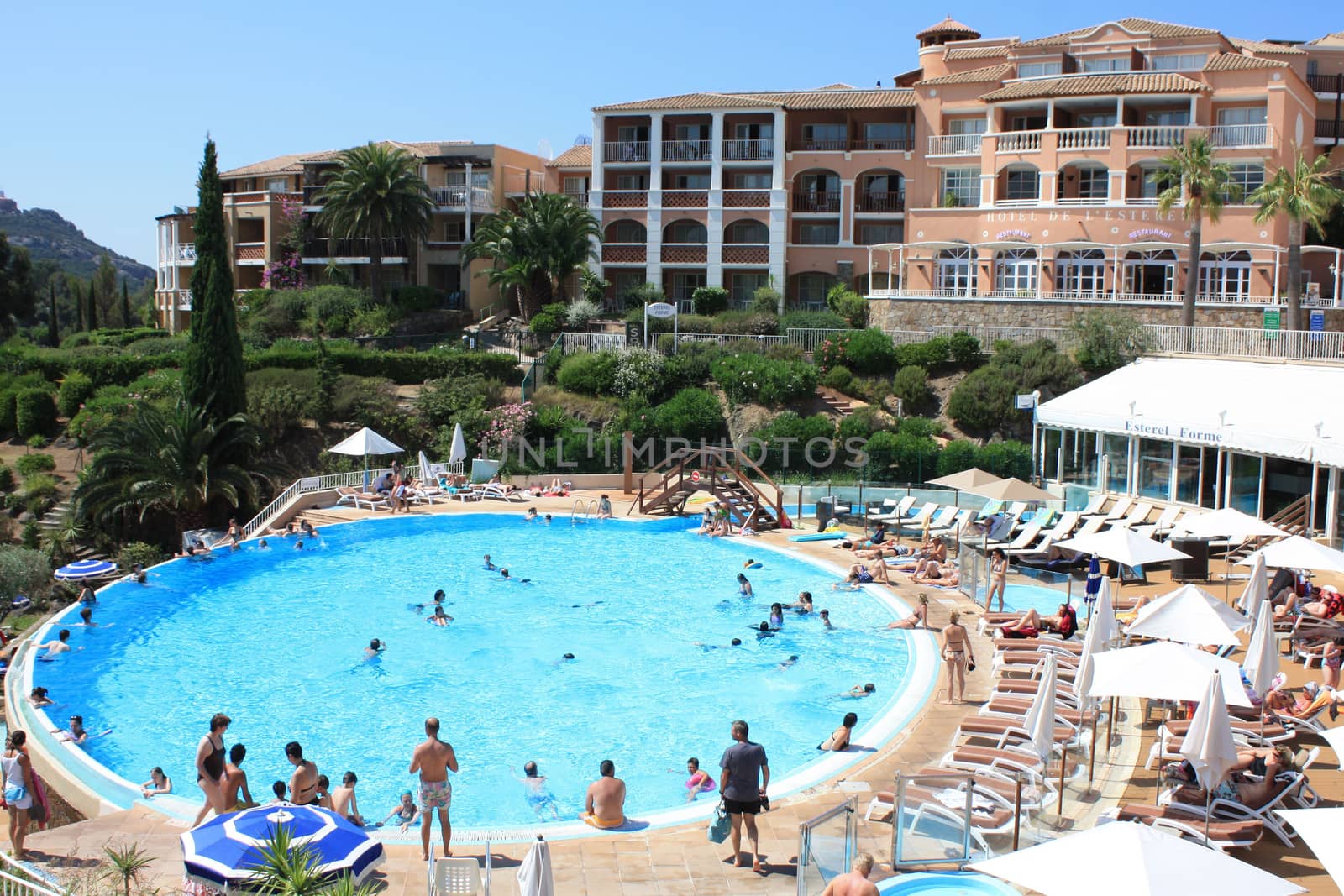 People swimming and getting tanned by a swimming pool  at a French hotel