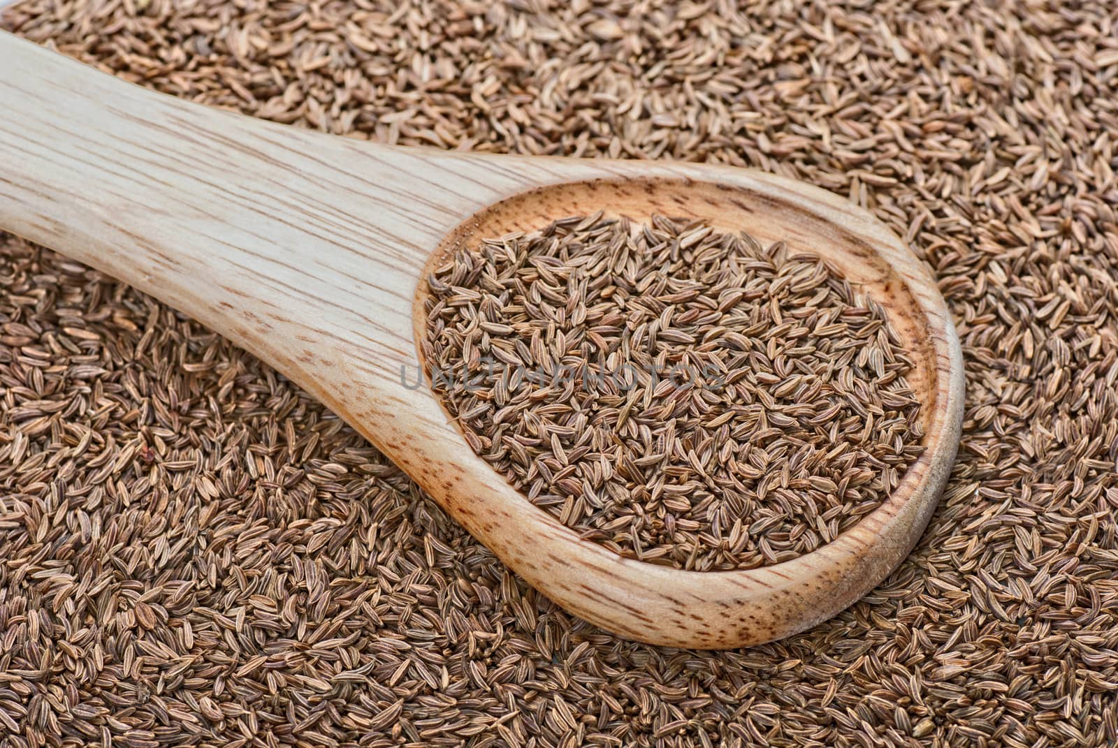 Cumin background with a wooden spoon