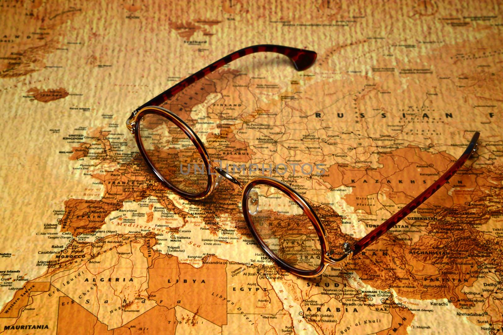 Photo of glasses on a map of a world, antique style. May be used as illustration for traveling theme.