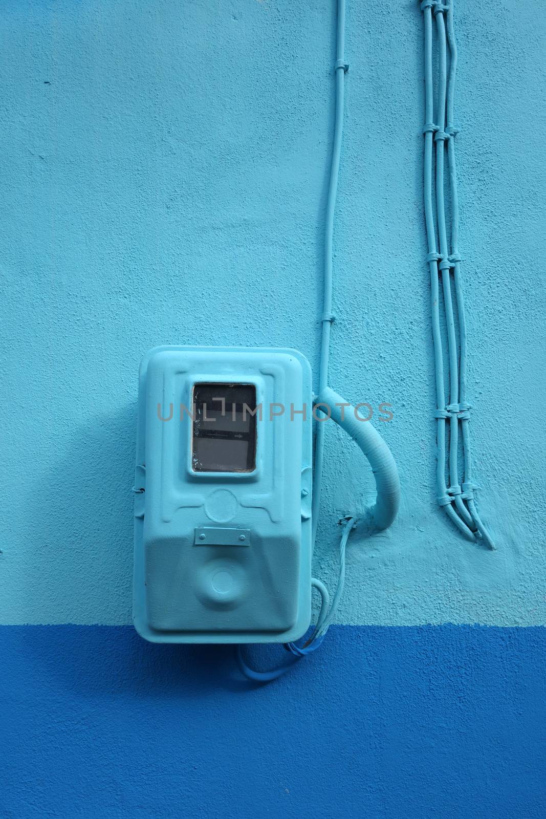 Electricity meter painted blue in harmony with the wall in Greece