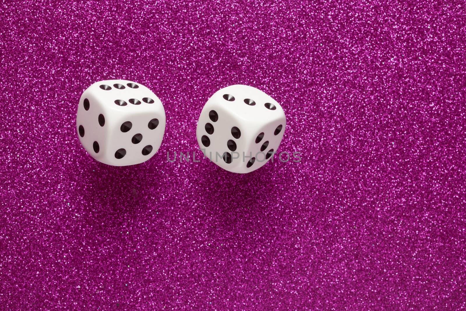 Rolling white dice over purple glittering surface