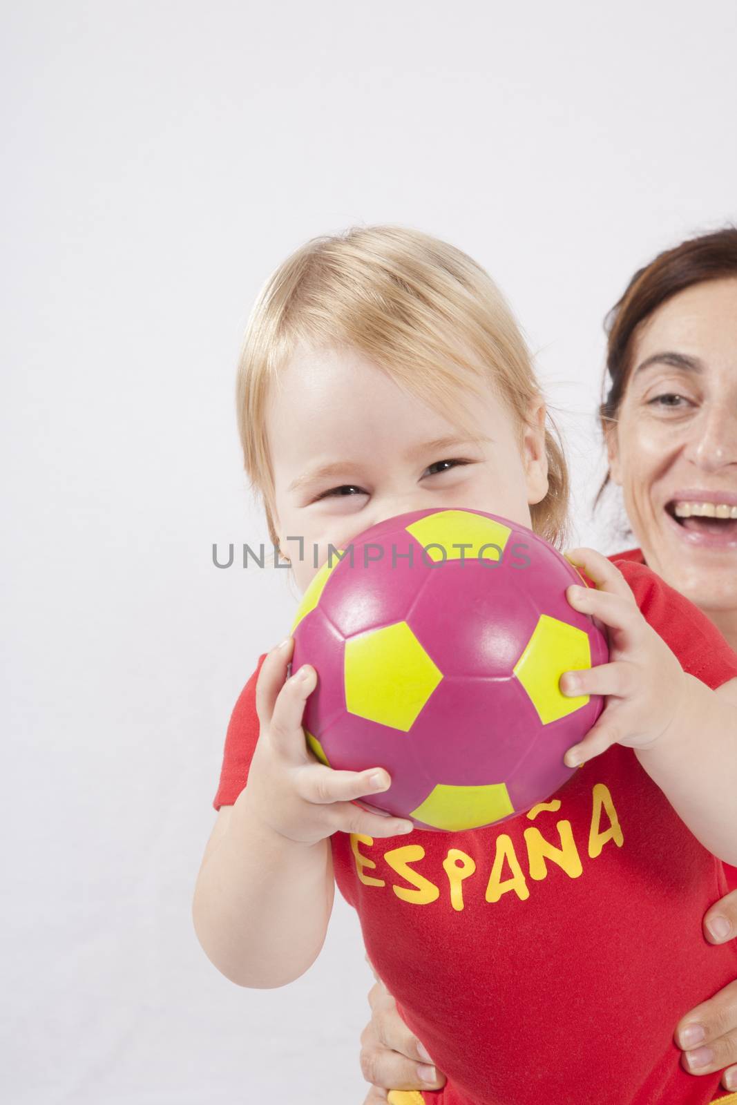 happy blonde baby sixteen month old and mother with red shirt of Spanish soccer team with ball