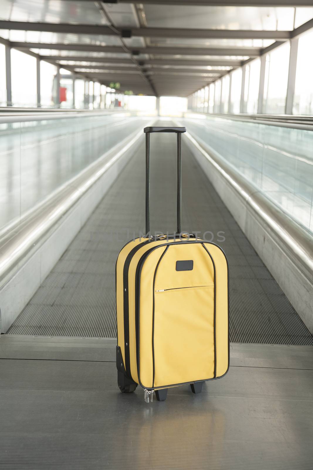 lonely yellow suitcase with black handle at walkway inside airport hall