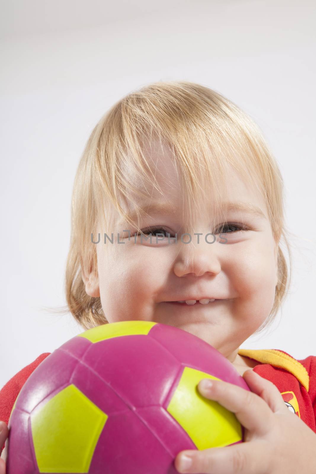 smiling lovely face blonde baby sixteen month old with red shirt of Spanish soccer team and ball