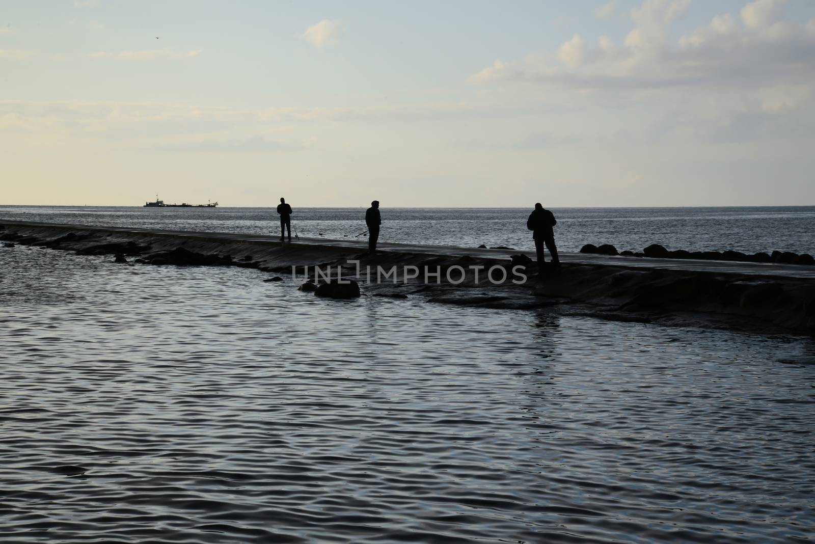 Photo of fishers silhouettes at pier. Taken in Riga.