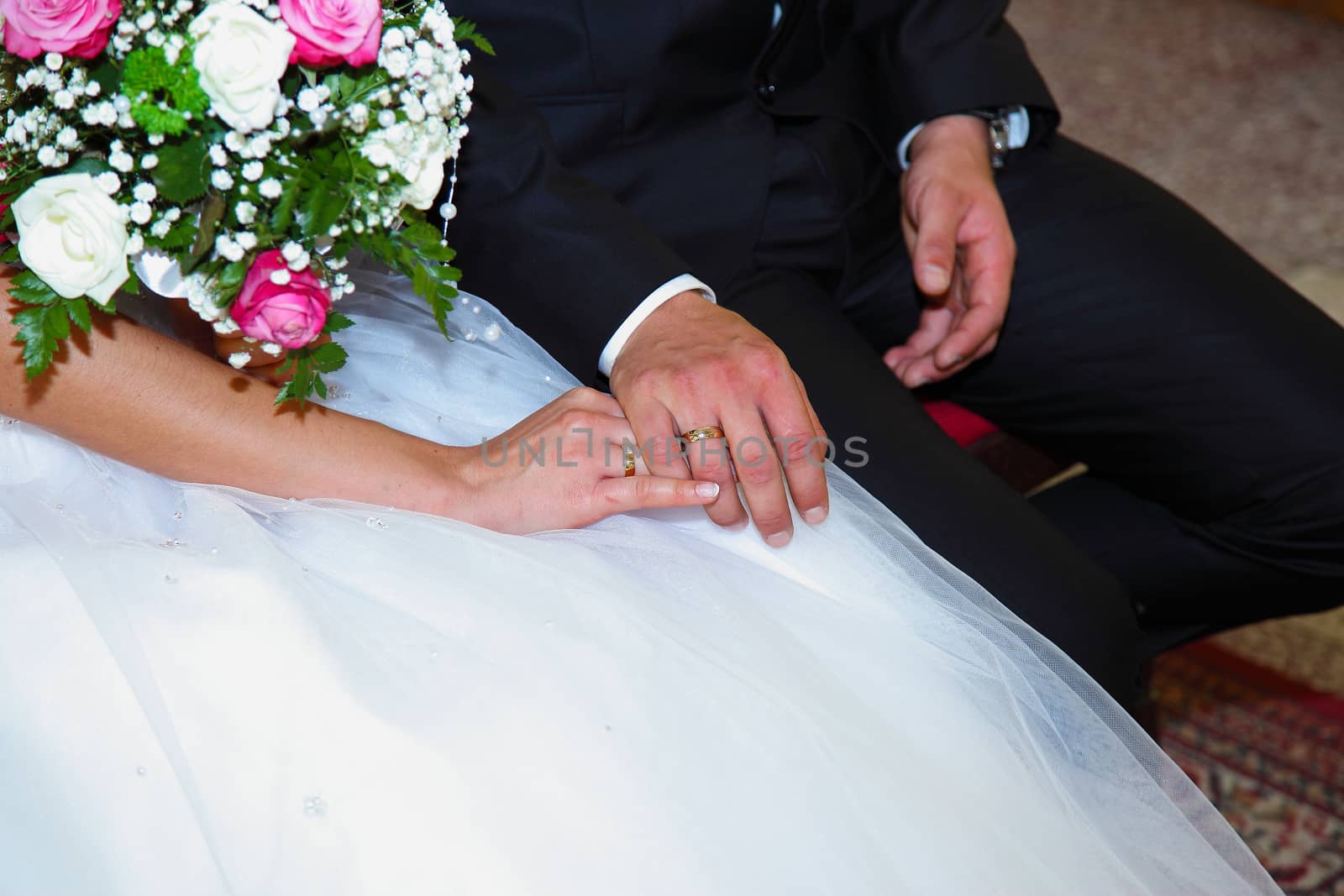 Bride keeping grooms hand during wedding ceremony in the church