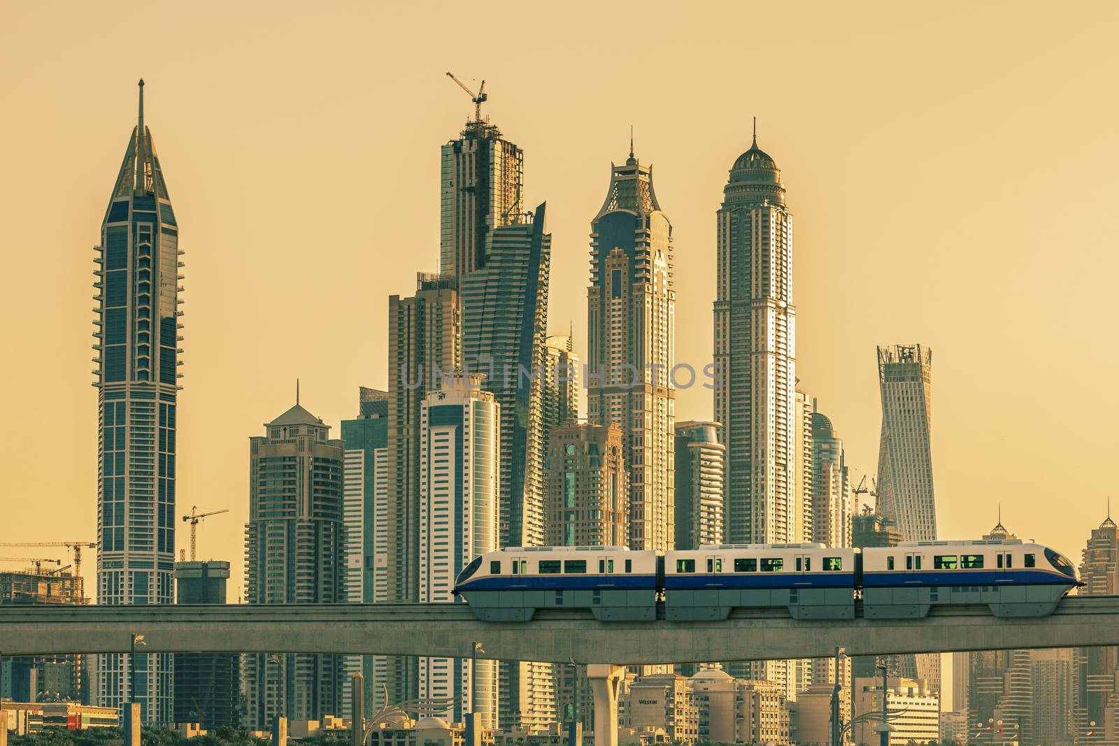 View of Dubai with subway and skycrapers at sunset.