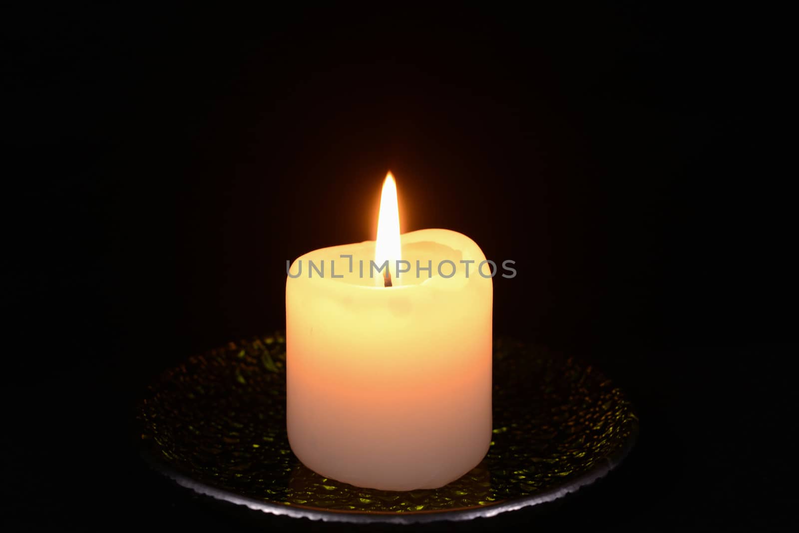 Photo of a burning candle on a black background. Object photography.