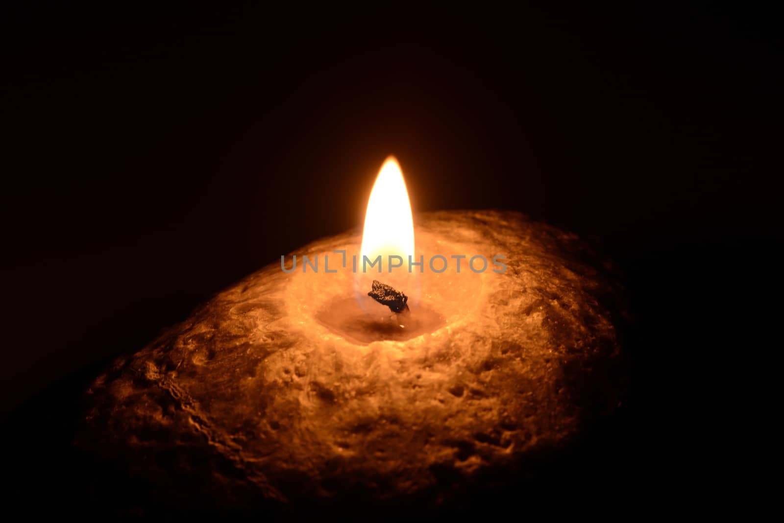 Photo of a burning candle on a black background. Object photography.