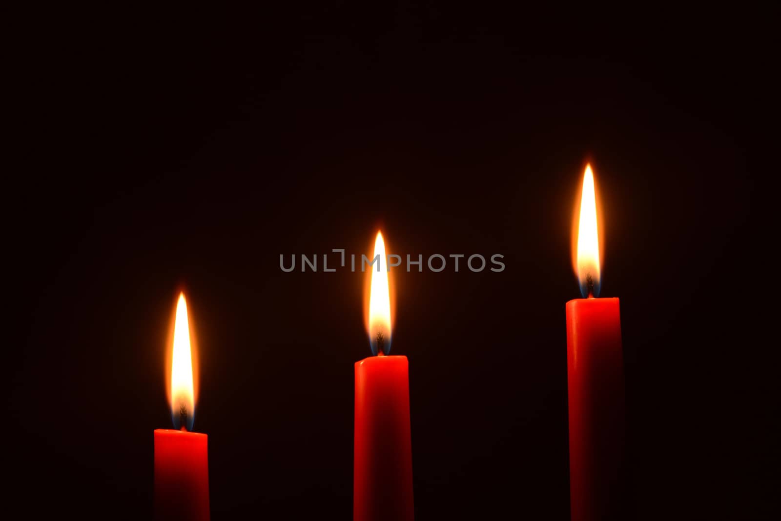 Photo of three red candles on a black background. Object photography.