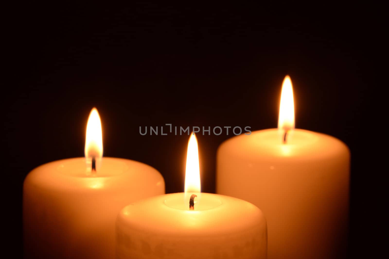 Photo of three candles on a black background. Object photography.