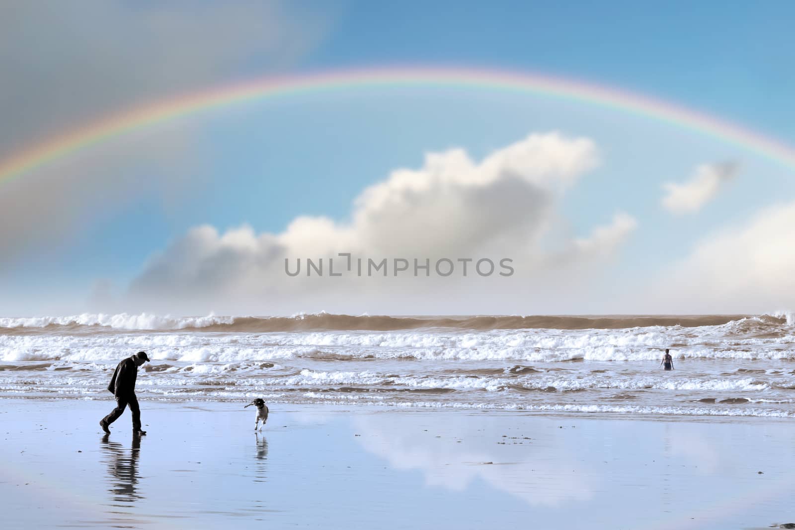 one man and his dog on Ballybunion beach county Kerry Ireland with a rainbow