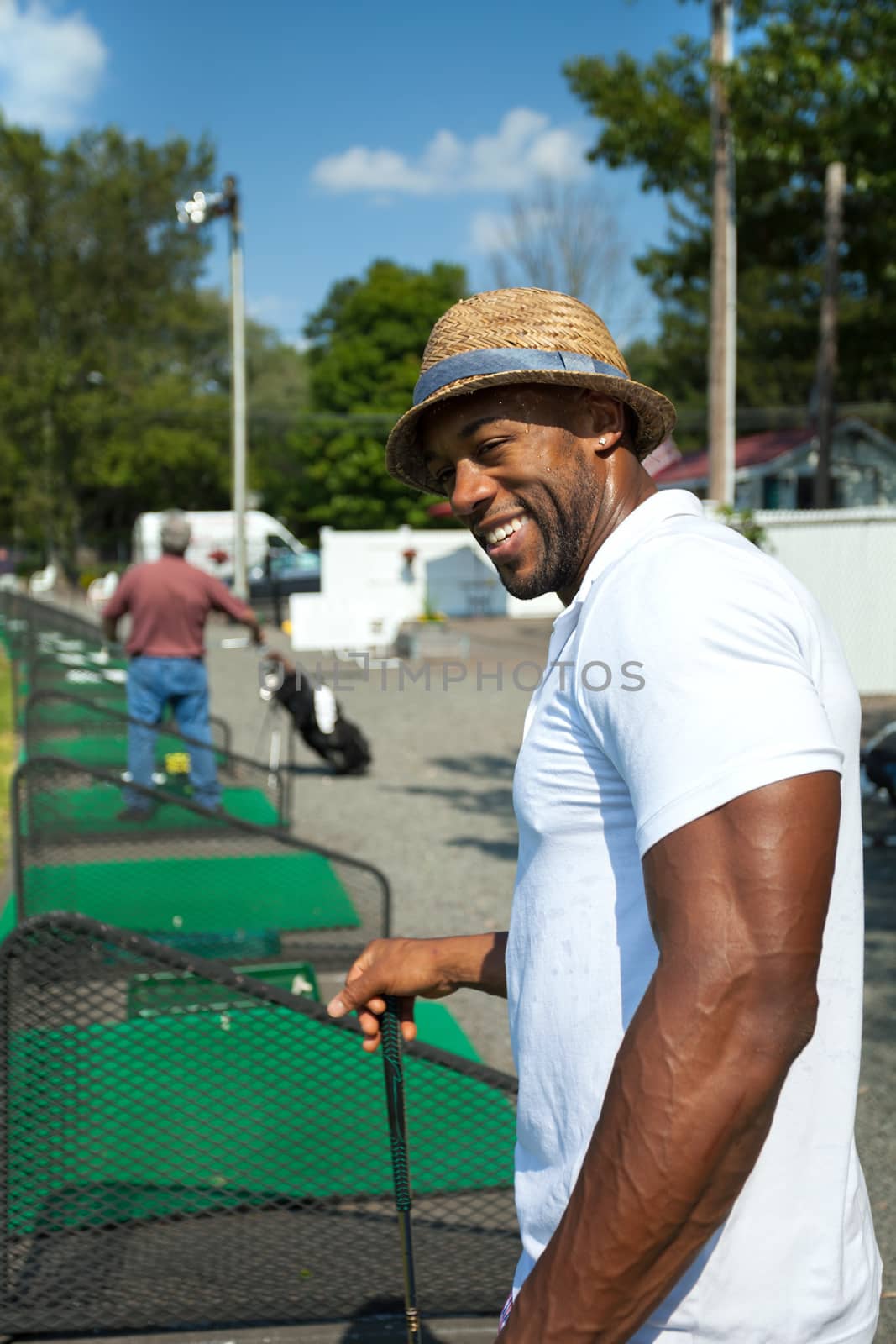 Athletic golfer swinging at the driving range dressed in casual attire.