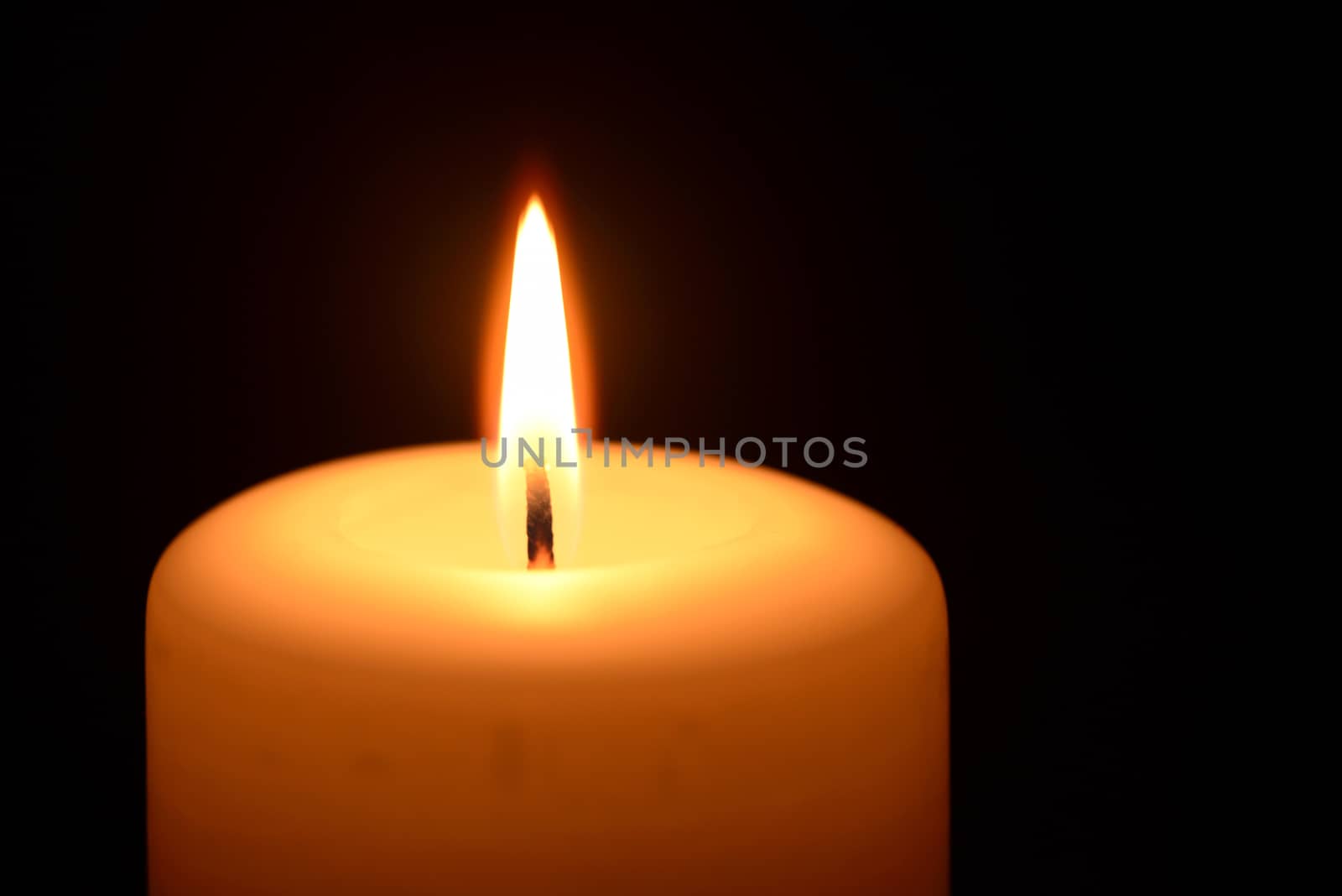 Photo of a burning candle on a black background. Objects photography.