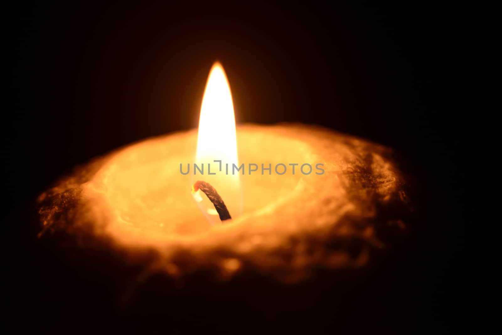 Photo of a burning candle on a black background. Objects photography.