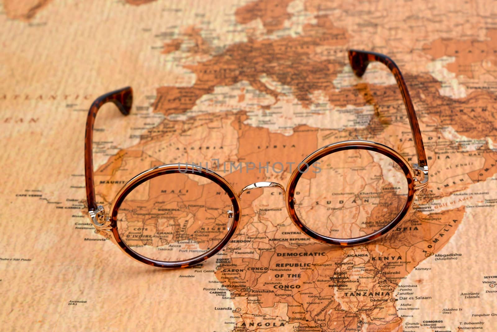 Photo of glasses on a map of a world, antique style. Focus on Africa. May be used as illustration for traveling theme.