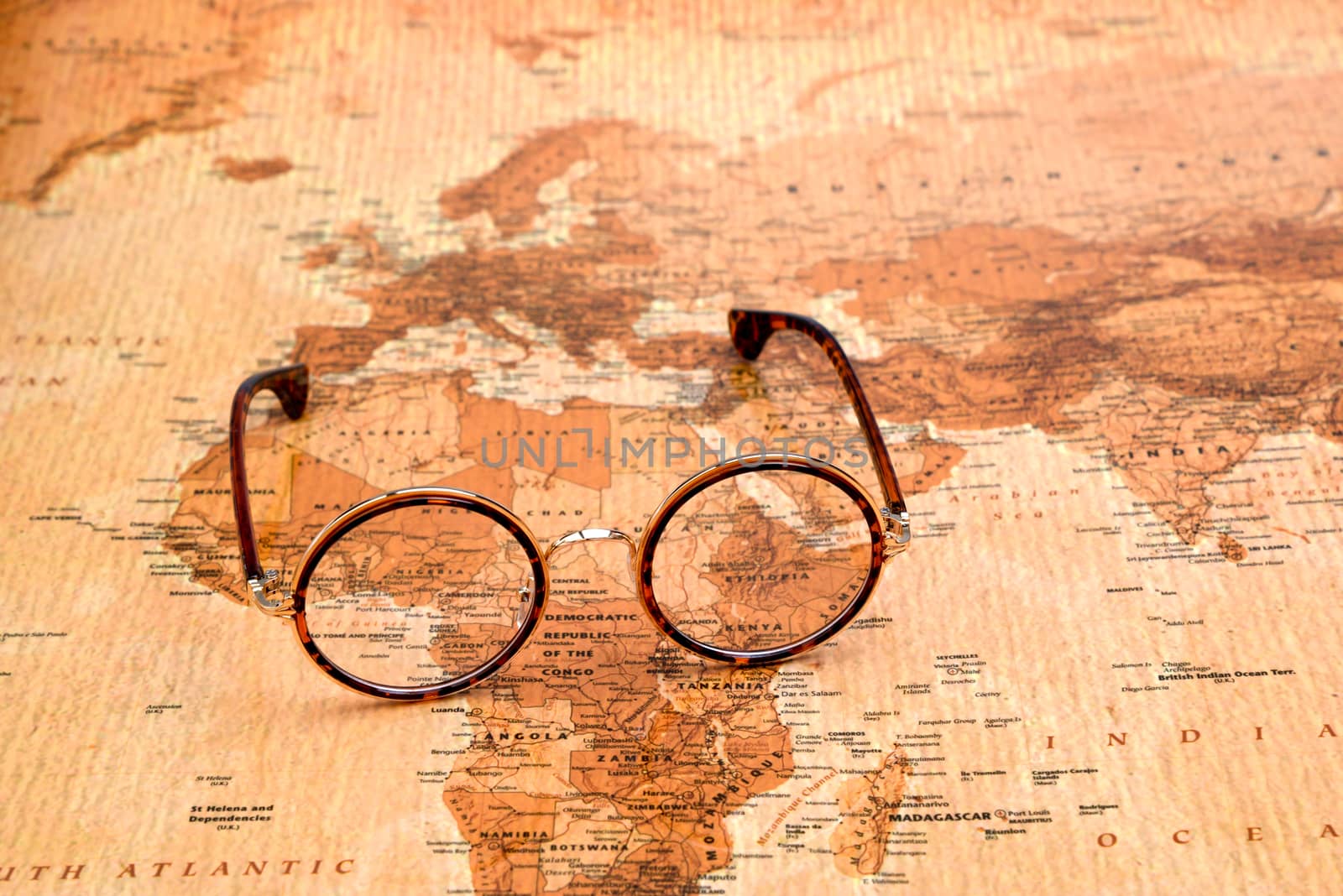 Photo of glasses on a map of a world, antique style. Focus on Africa. May be used as illustration for traveling theme.