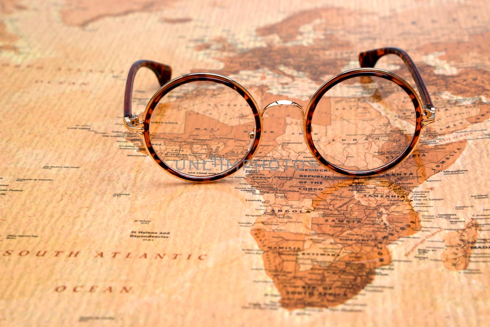 Photo of glasses on a map of a world, antique style. Focus on Africa. May be used as illustration for traveling theme.
