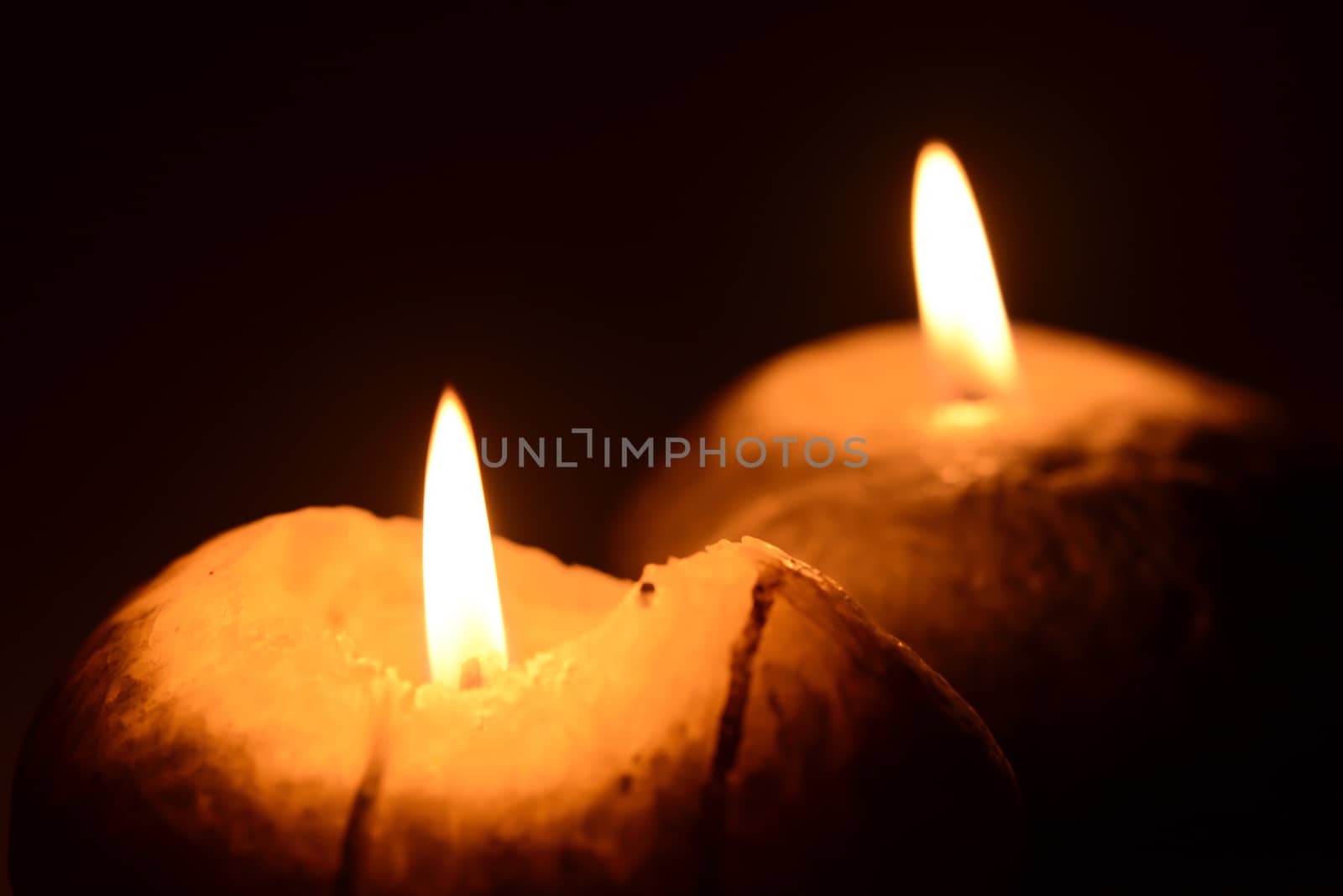 Photo of two burning candles on a black background. Objects photography.