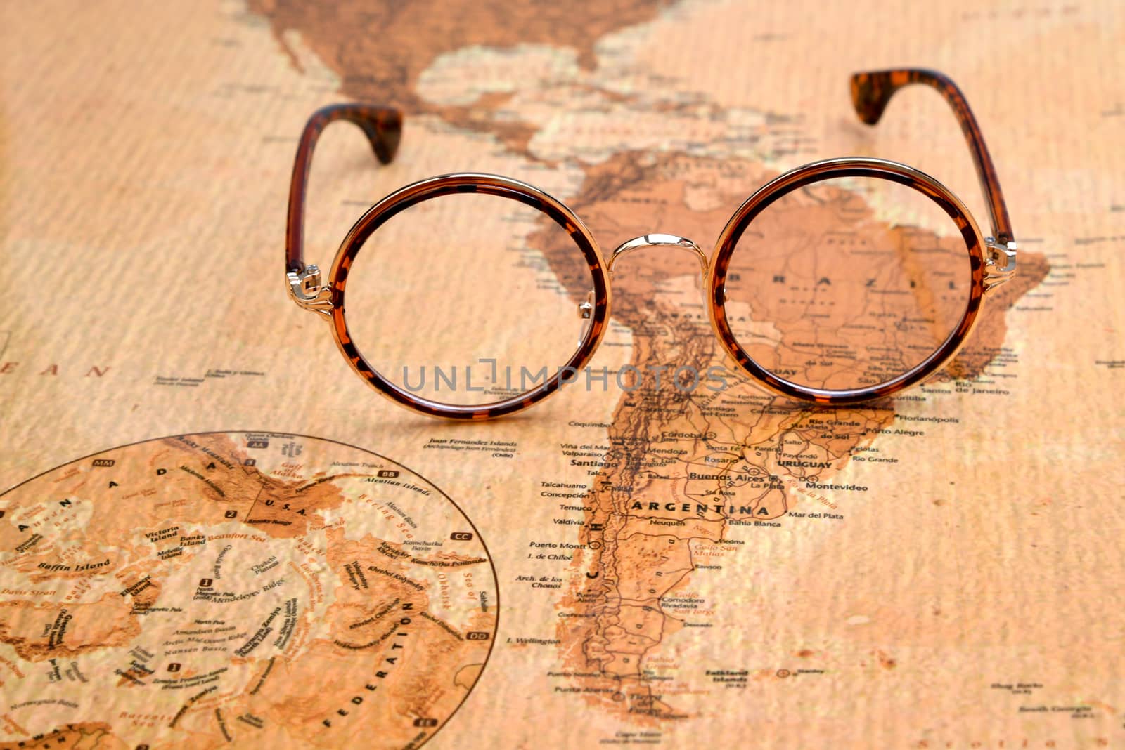 Photo of glasses on a map of a world, antique style. Focus on Brazil. May be used as illustration for traveling theme.