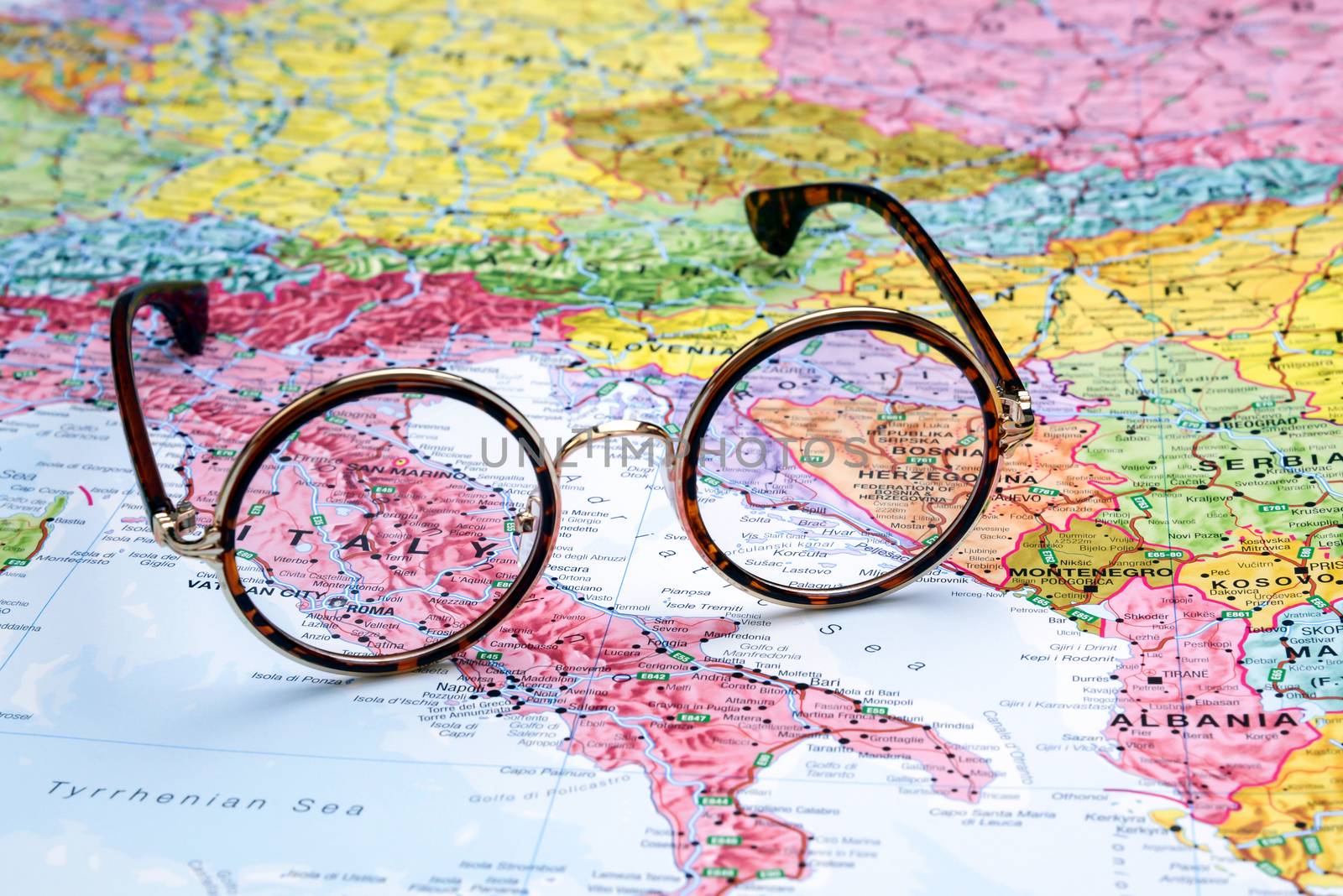 Photo of glasses on a map of europe. Focus on Italy. May be used as illustration for traveling theme.